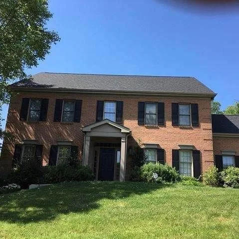 Brick two-story home with new windows and roofing on a sunny day