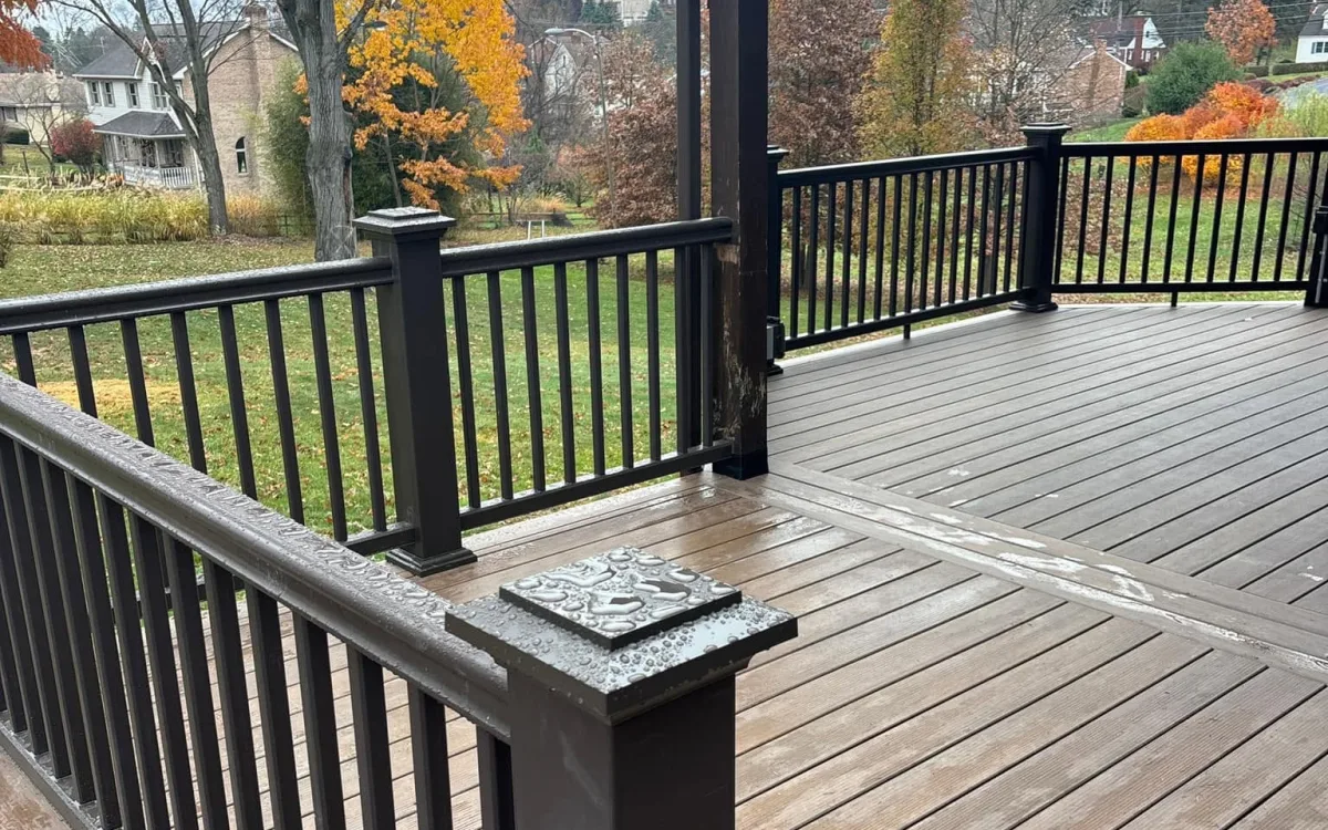 Composite deck with black metal railing and a covered pavilion overlooking a fall backyard